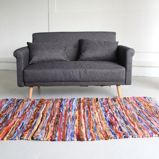 Multicolored striped rug on a white floor with a gray sofa in the background