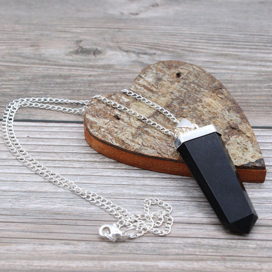 Black and silver pendant on a chain against a wooden background