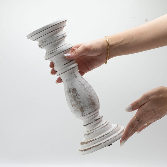 Person holding a white distressed candlestick against a light background