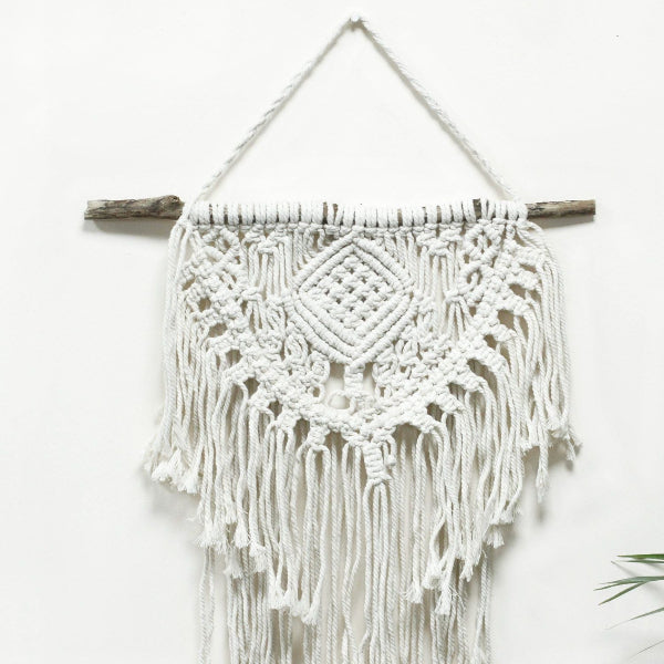 Macrame wall hanging with white yarn and wooden sticks on a white background