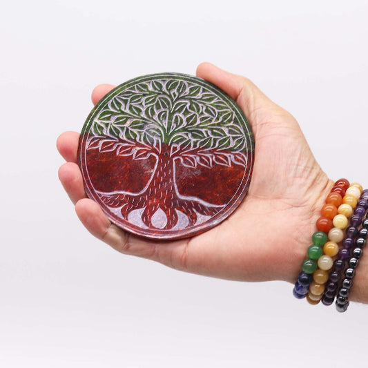Hand holding a colorful tree of life stone against a white background