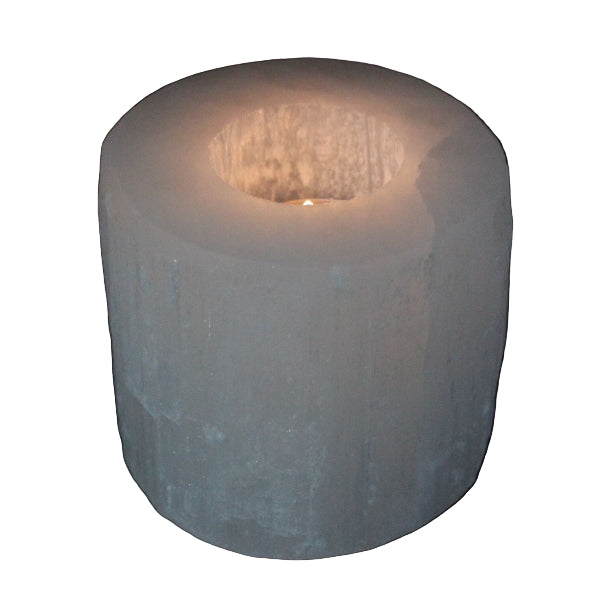 Cylindrical candle holder with a lit candle on a black background