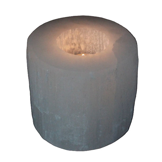 Cylindrical candle holder with a lit candle on a black background