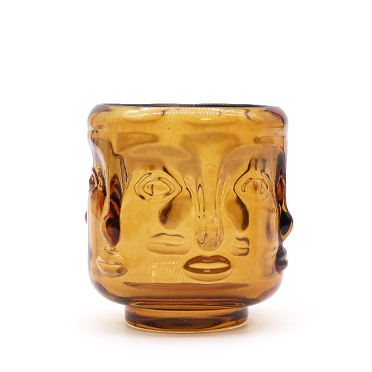 Amber glass buddha candle holder with face design on a white background