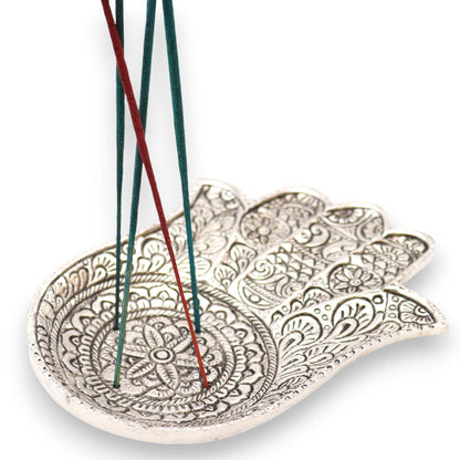 Decorative leaf-shaped incense holder with incense sticks on a white background