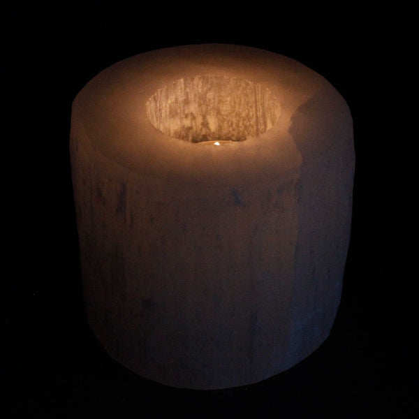 Candle in a glass holder on a black background
