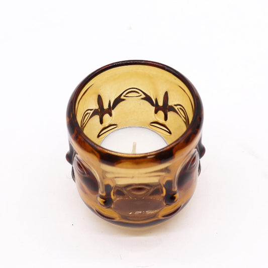 Amber glass buddha candle holder with face design on a white background