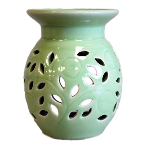 Light green ceramic vase with a perforated design on a white background