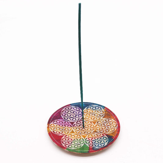 Incense stick on a colorful circular holder with geometric design on a white background