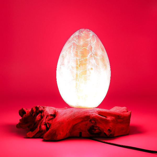 Egg-shaped light on a wooden base against a red background