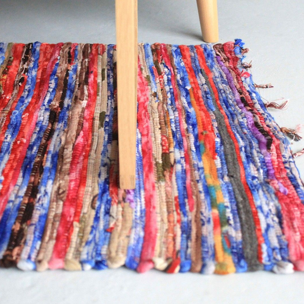 Colorful fabric with tassels on a wooden stick against a light background