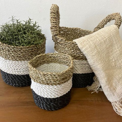 Set of woven baskets with a plant and towel on a wooden surface