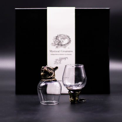 Two glass containers with gold animal-shaped bases in front of a black box labeled 'Mystical Creatures'.