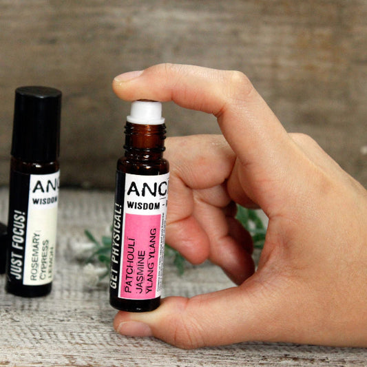 Hand holding a small rollerball bottle labeled 'ANC Wisdom' with another bottle in the background.