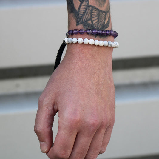 Hand wearing two bracelets with a blurred background