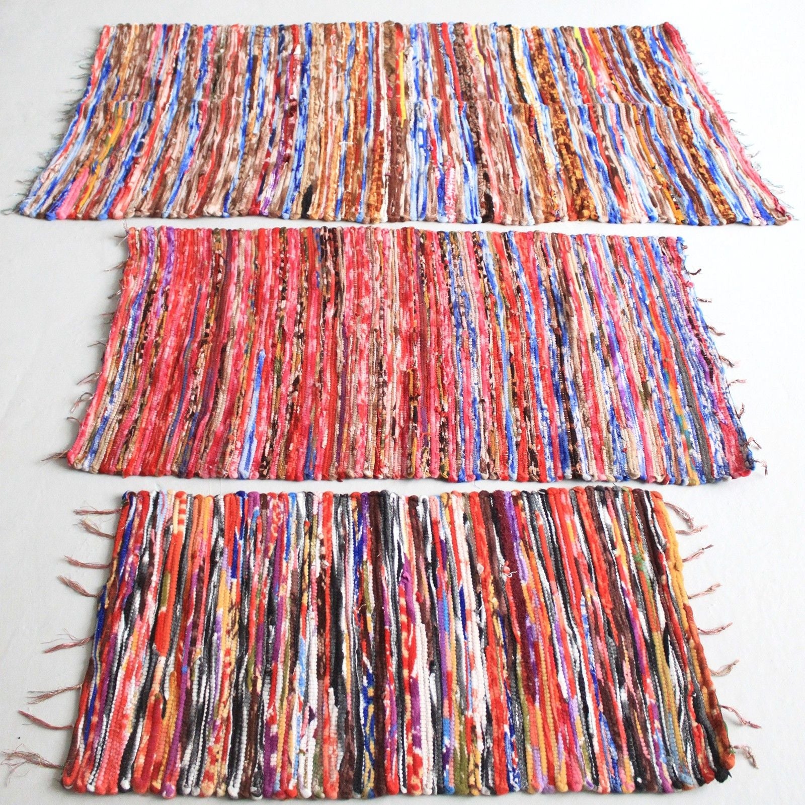 Three colorful woven placemats on a light gray background