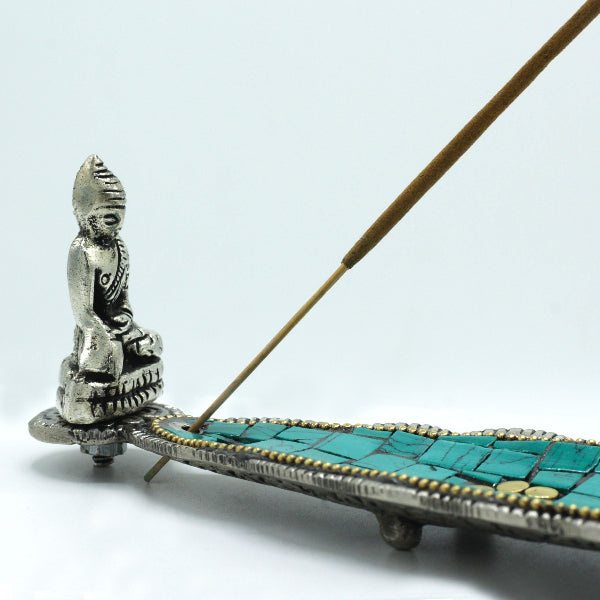 Decorative incense holder with a silver figure and turquoise mosaic on a white background