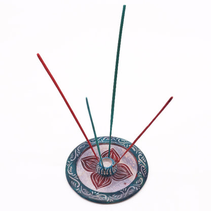 Incense holder with red and green incense sticks on a white background