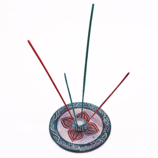 Incense holder with red and green incense sticks on a white background