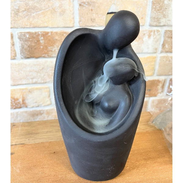 Black ceramic water fountain with flowing water against a brick wall background
