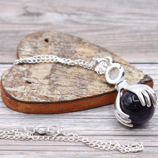 Silver bracelet with a black stone pendant on a wooden heart-shaped block