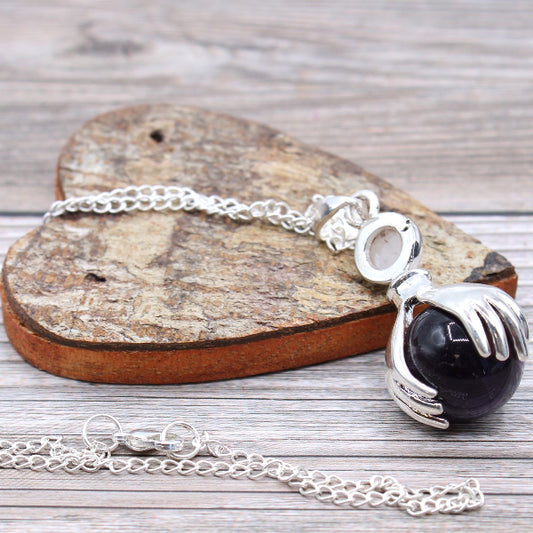 Silver bracelet with a black stone pendant on a wooden heart-shaped block