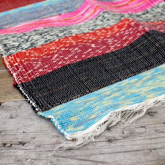 Colorful woven fabric samples on a wooden surface