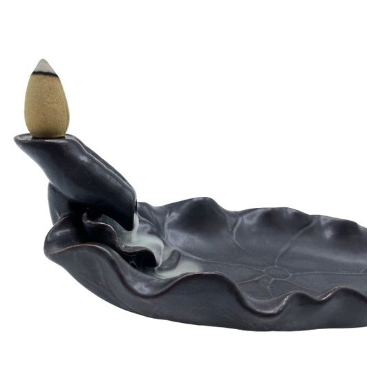 Ceramic incense burner shaped like a leaf with a backflow incense stick on a white background