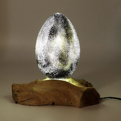 Decorative lamp with a textured glass egg on a wooden base against a neutral background