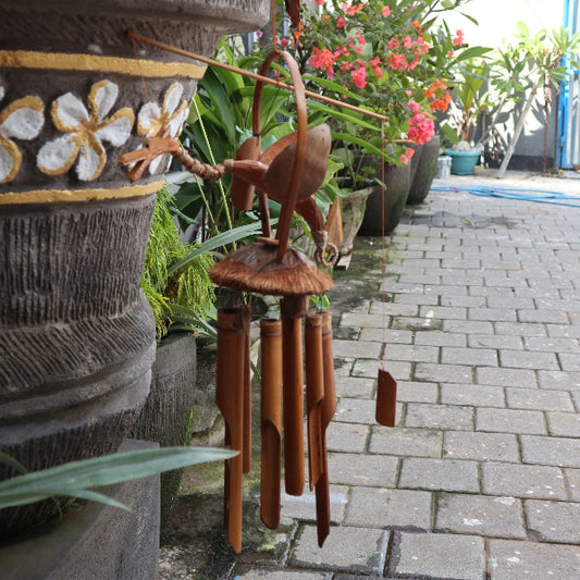 Wooden wind chime in front of decorative pots with floral patterns on a stone path.