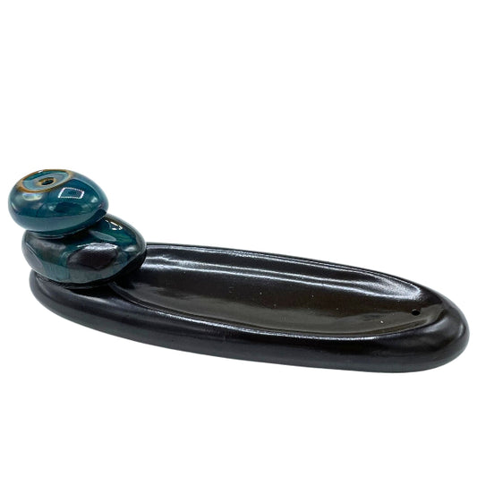 Black ceramic dish with a decorative green and blue handle on a white background