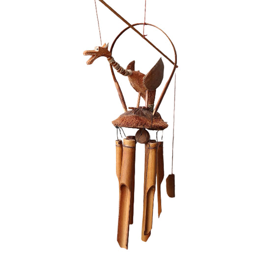 Rustic wind chime with wooden tubes and metal dragon-like figure on a gray wall.