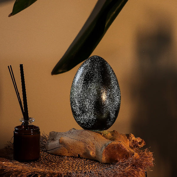 Decorative egg on a wooden base with a diffuser and leaves in the background