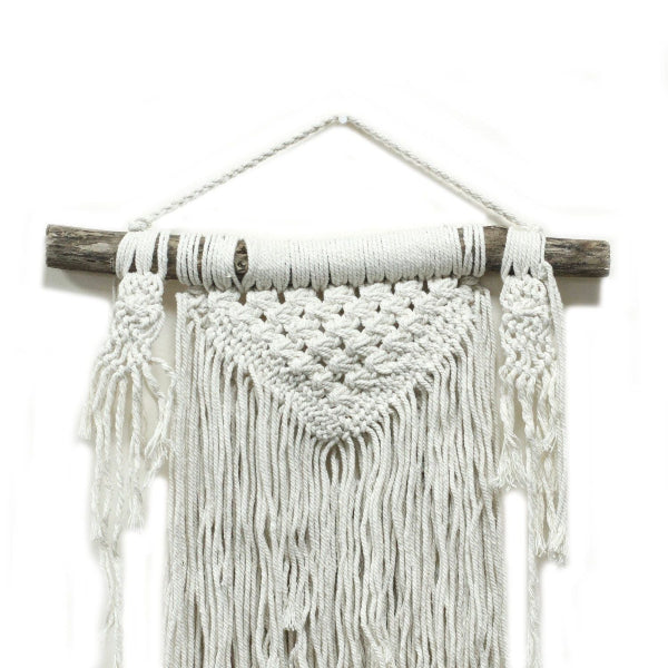 Macrame wall hanging with white yarn on a wooden stick against a white background