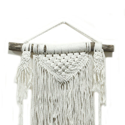 Macrame wall hanging with white yarn on a wooden stick against a white background