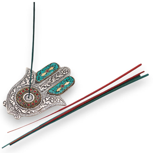 Decorative incense holder with intricate designs and two incense sticks on a white background