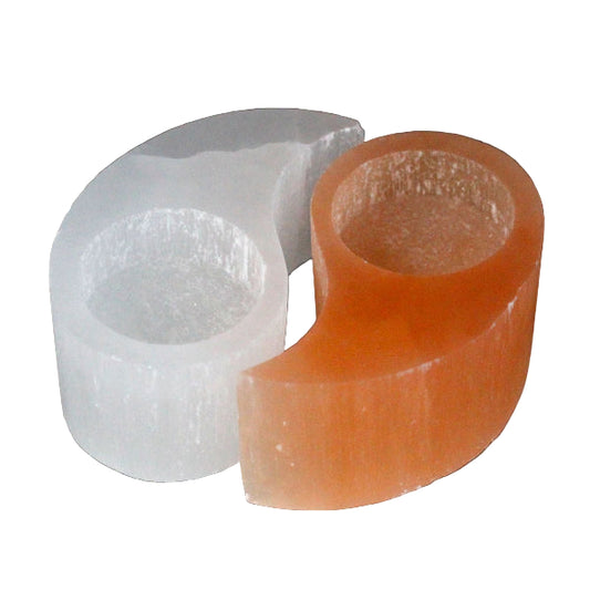 Two selenite candle colders one white and one orange, on a dark background