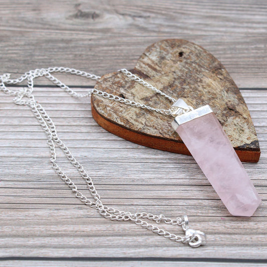 Necklace with a pink crystal pendant on a wooden surface