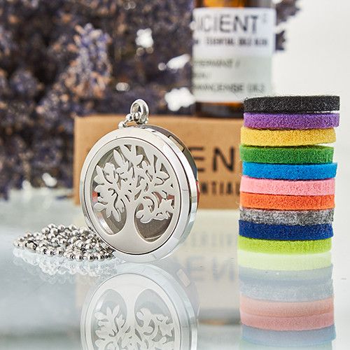 Silver tree-shaped locket with colorful hair ties on a reflective surface.