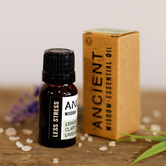 Essential oil bottle with 'Less Stress' label and packaging on a wooden surface.