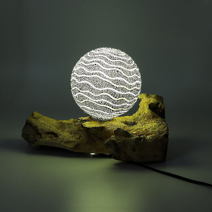Decorative lamp with wavy pattern on a wooden base against a dark background