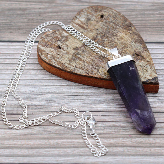 Amethyst crystal necklace with silver chain on a wooden surface