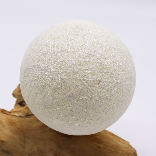 White yarn ball on a wooden block against a white background