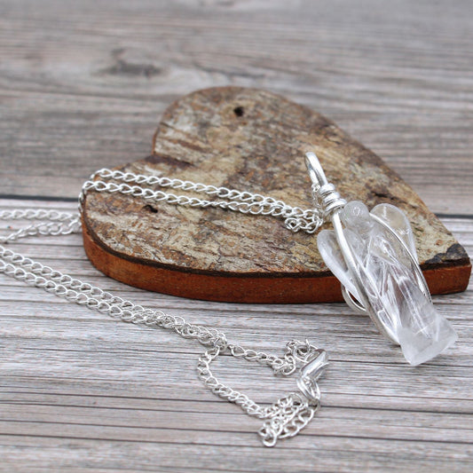 Silver necklace with a clear crystal pendant on a wooden surface
